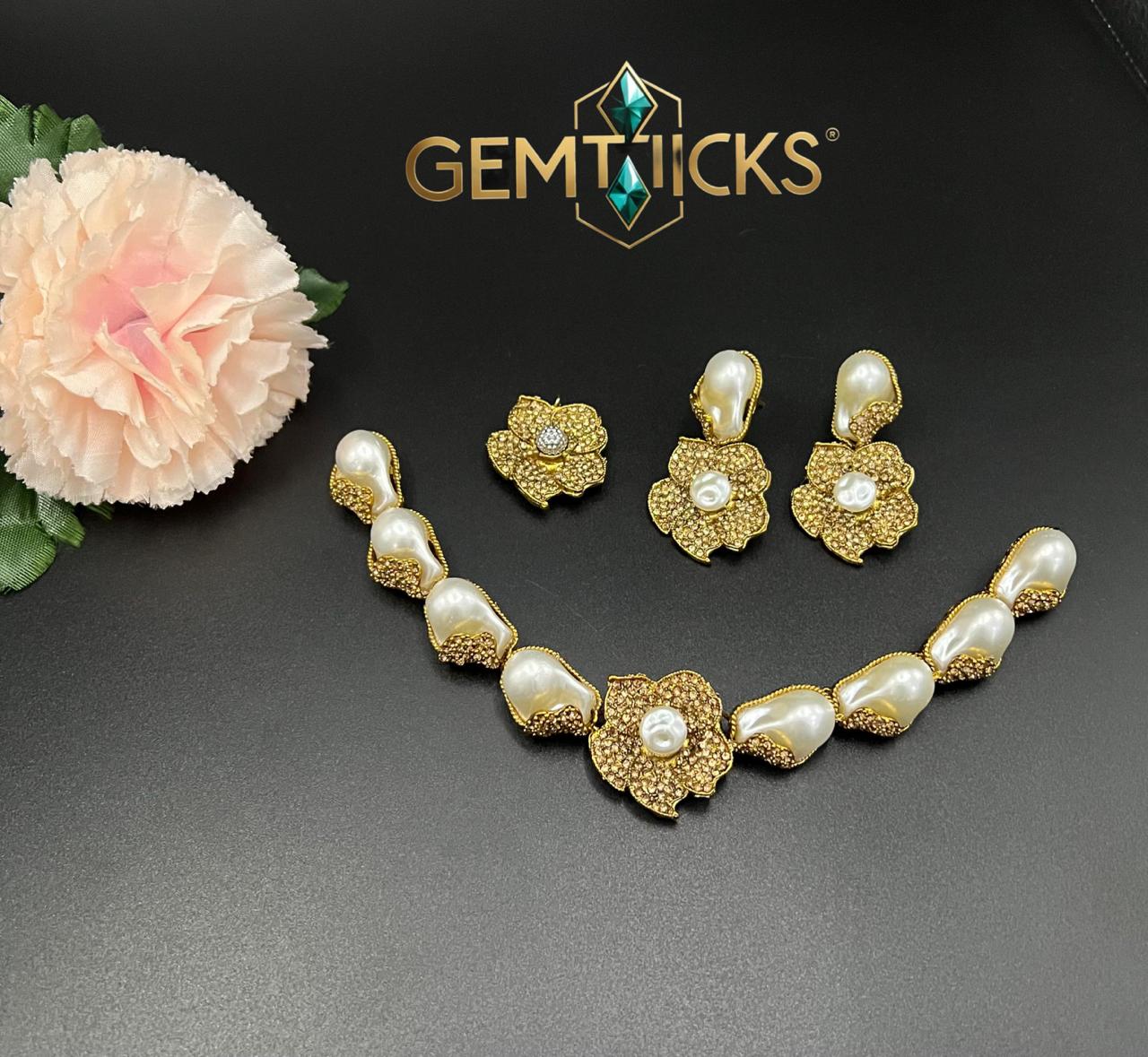 Gold and pearl jewelry set with flowers on a dark background, featuring the Gemticks brand.