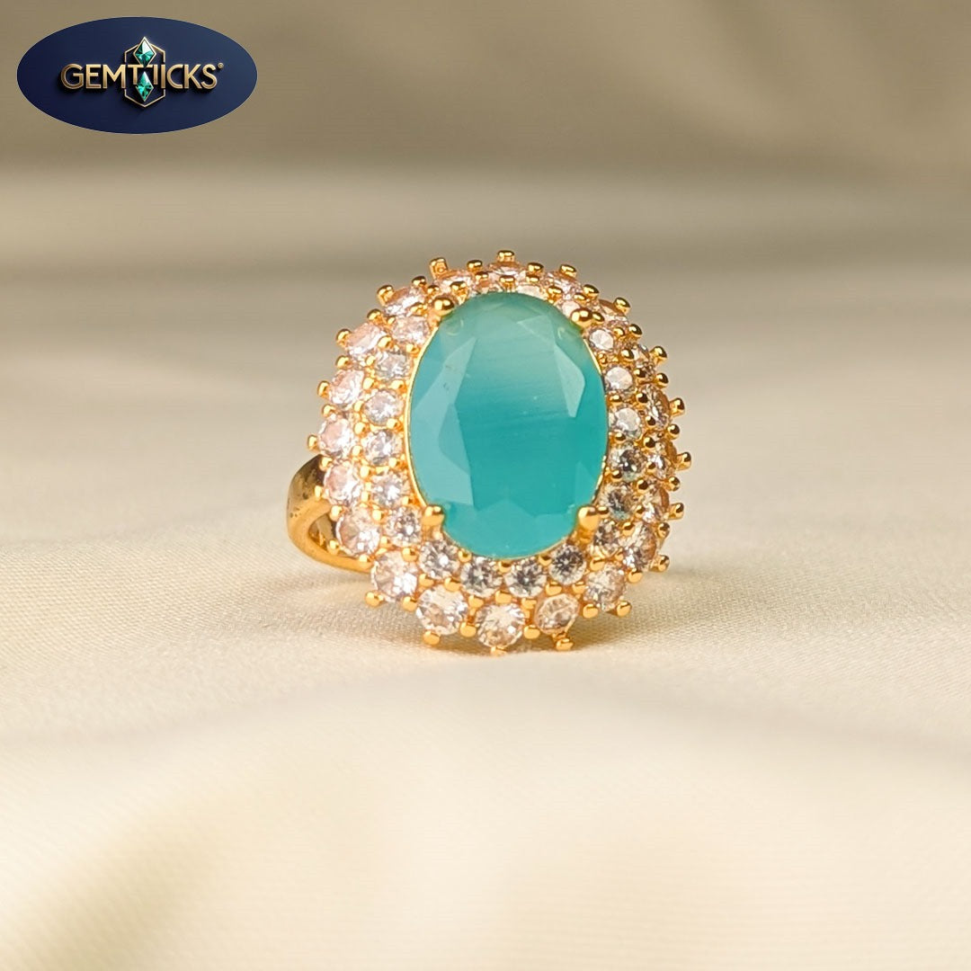 Gold ring with a turquoise stone and gemstones on a beige background, featuring the Gemticks brand.