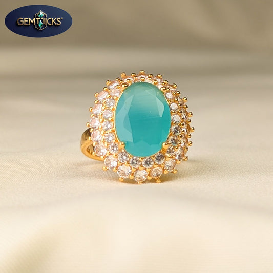 Gold ring with a turquoise stone and gemstones on a beige background, featuring the Gemticks brand.