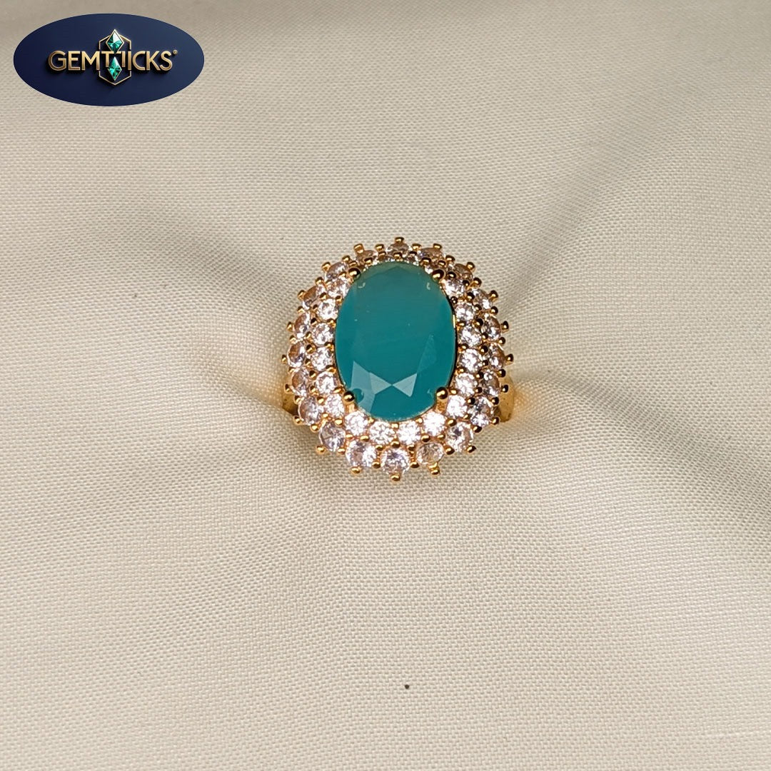 Gold ring with a turquoise gemstone on a beige fabric background, featuring Gemticks logo.