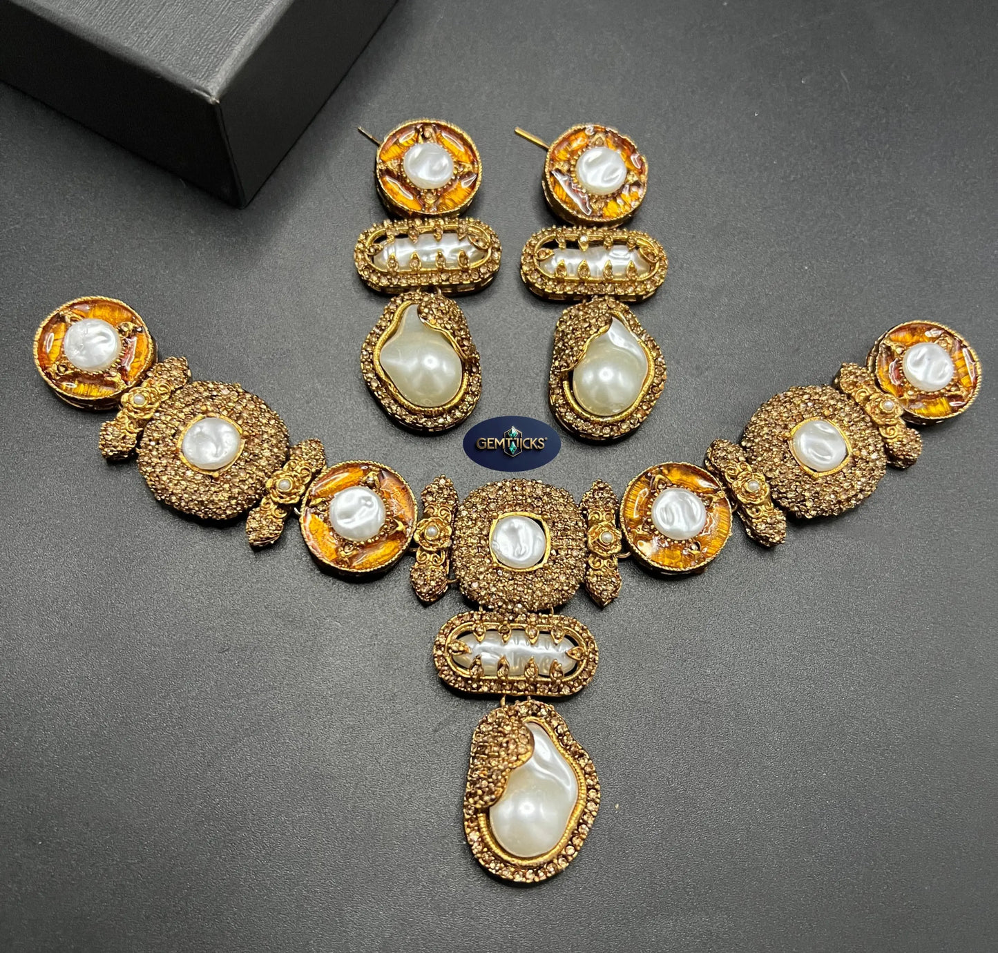 Gold necklace with pearls and matching earrings on a dark surface