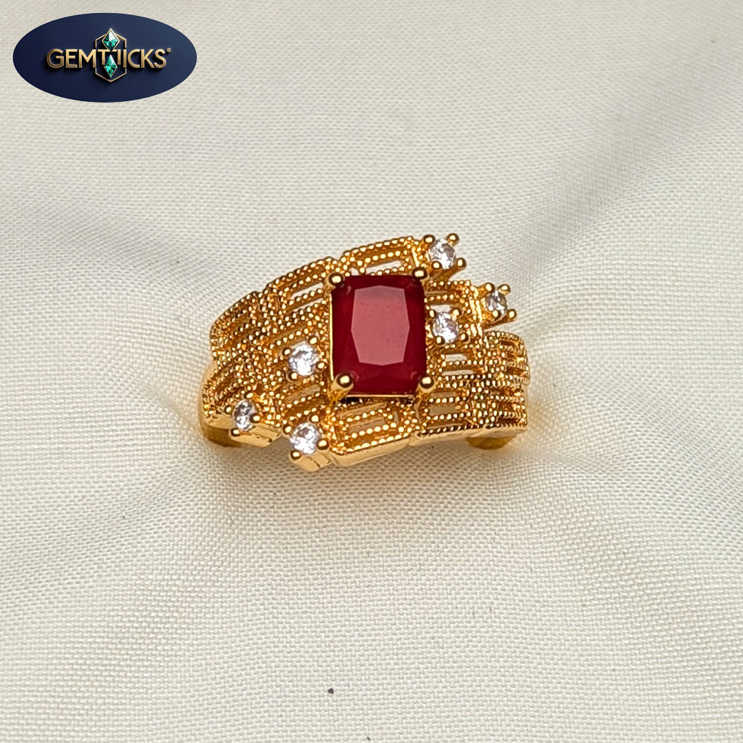 Gold ring with a red gemstone and small diamonds on a beige background, featuring Gemwicks logo.