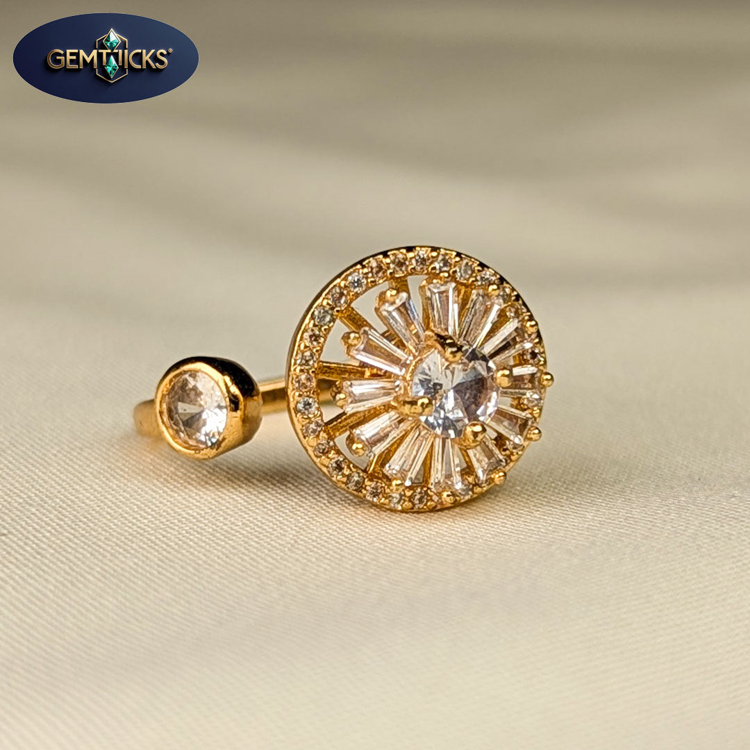 Gold earring with clear gemstones on a beige fabric background, featuring Gemticks logo.