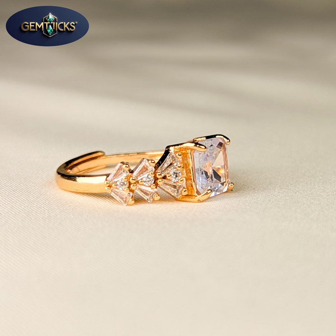 Gold ring with clear gemstones on a beige background, featuring Gemticks logo.